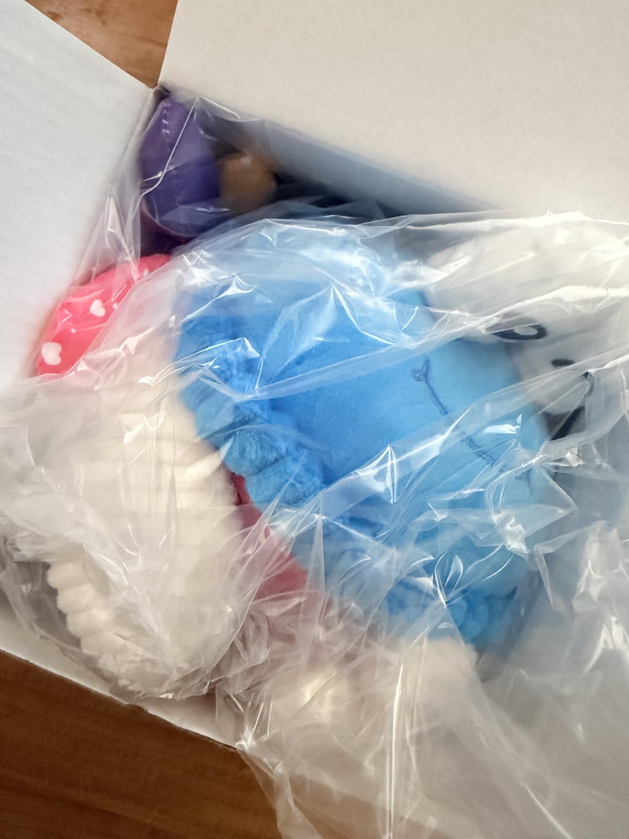 Blue plush crab toy still in its plastic wrap inside the shipping box
